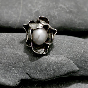 Hand carved Sterling silver rose ring with two layers of individually shaped rose petals, gently oxidised before a baroque pearl is carefully set and re-polished. Every piece is is a unique design. Floral jewellery handmade in England.