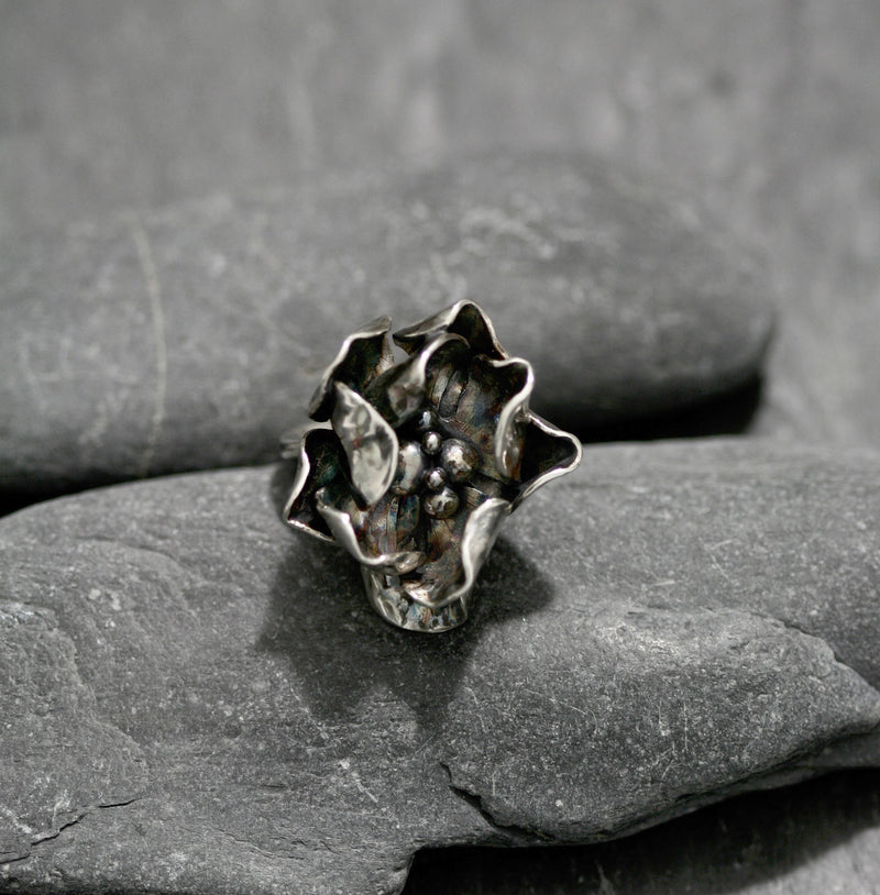 A Sterling silver hand carved ring with two layers of individually textured and shaped rose petals. Treated with gentle oxidation techniques and re-polished making every piece a unique design in its own right.