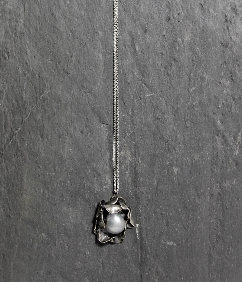 Hand carved Sterling silver rose necklace with two layers of individually shaped rose petals, gently oxidised before a baroque pearl is carefully set and re-polished. On an 18 inch Silver trace chain with a handmade hook catch.