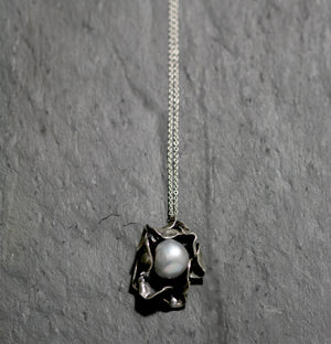 Hand carved Sterling silver rose necklace with two layers of individually shaped rose petals, gently oxidised before a baroque pearl is carefully set and re-polished. On an 18 inch Silver trace chain with a handmade hook catch.